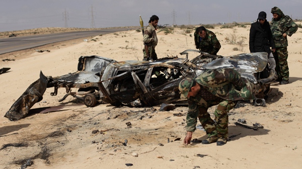 A Libyan rebel collects the charred remains of rebels who were allegedly killed in NATO coalition airstrike overnight, as others inspect the damaged vehicle along the front line near Brega, Libya, Saturday, April 2, 2011. (AP / Altaf Qadri)