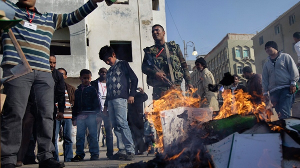 Men burn copies of Libyan leader Moammar Gadhafi's "Green Book" at a rally to protest against deaths caused by Gadhafi's forces and his continued refusal to step down, on the corniche in Benghazi, Libya Saturday, April 2, 2011. (AP / Ben Curtis)