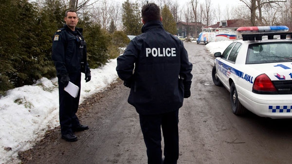 Police officers stand at the scene in Laval, Que., near Montreal, Monday, April 4, 2011, where three-year-old autistic boy Adam Benhamma went missing on Sunday, April 3, 2011. (Graham Hughes / The CANADIAN PRESS)