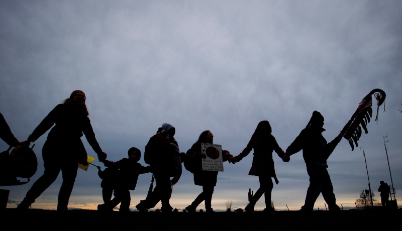 First Nations Idle No More protesters hold hands and dance in a circle during a demonstration at the Douglas-Peace Arch crossing on the Canada-U.S. border near Surrey, B.C., on Saturday Jan. 5, 2013. (The Canadian Press/Darryl Dyck)