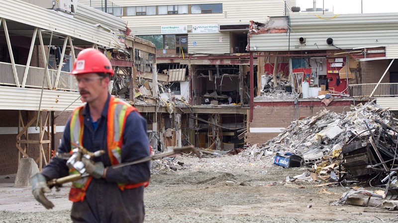 A worker walks back from the rubble after Ontario Premier Dalton McGuinty speaks to the community of Elliot lake regarding the recovery of two bodies at the Algo Centre Mall in Elliot Lake, Ont., on June 27, 2012. (Nathan Denette / THE CANADIAN PRESS)