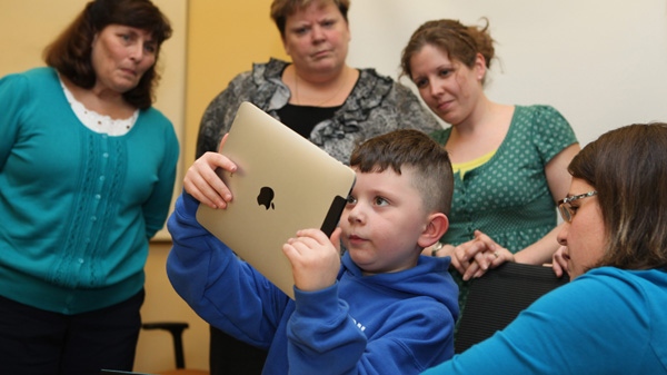 Kindergartener Lucius Rice, 6, center, demonstrates to Kindergarten teachers Sue larue, left to right, Kelly McCarthy and Amy Himerl, how to uses an iPad as literacy teacher Maurie Dufour, right, looks on, Tuesday, April 12, 2011 in Auburn, Maine. (AP Photo/Joel Page)