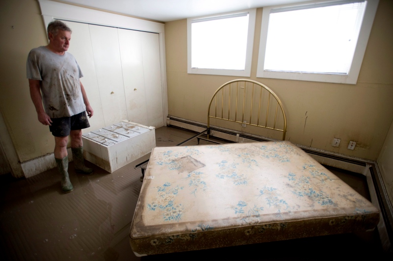 Homeowner Glenn Tibbles looks at the damage done by floodwaters to his home near downtown Calgary, Alta., Sunday, June 23, 2013. (Jonathan Hayward / THE CANADIAN PRESS)