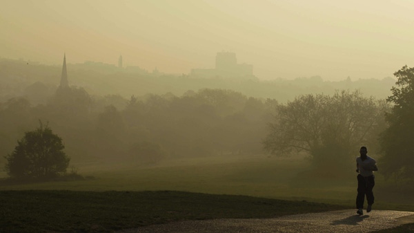A man jogs on Parliament Hill on Hampstead Heath as smog can be seen in the distance in London, Friday, April 22, 2011. (AP Photo/Matt Dunham)