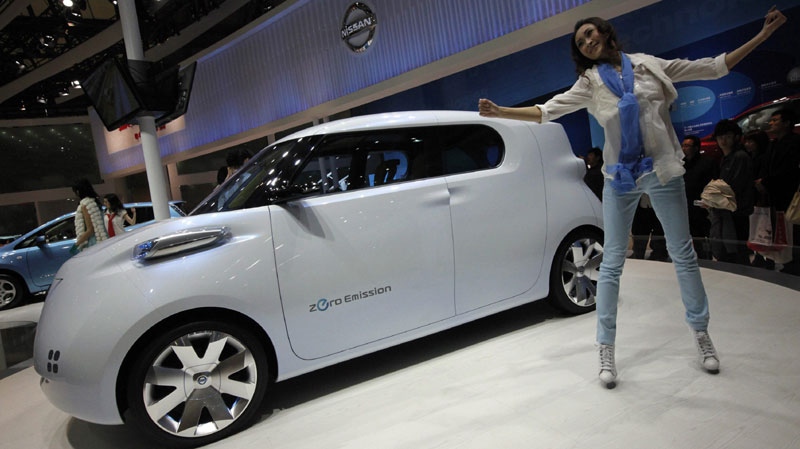 An artist performs next to a Nissan Townpod at the Shanghai International Auto Show Thursday, April 21, 2011 in Shanghai, China. (AP Photo/Eugene Hoshiko)