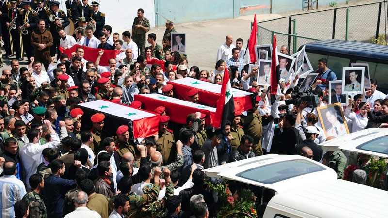 In this photo released by the Syrian official news agency SANA, Syrian military police carry coffins as they prepare to send the bodies of fifteen killed soldiers and security force members to their hometowns for burial, at a military hospital in Damascus, Syria, Tuesday, April 26, 2011.