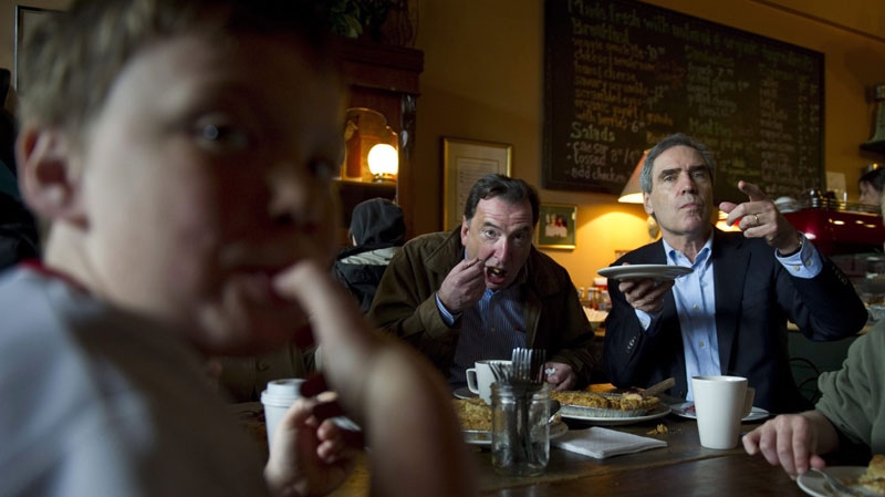 Noah Ennis, 11, licks his thumb as he shares a pie with Liberal Leader Michael Ignatieff and local candidate Dan Veniez at the Savary Island Pie Co. Monday, April 25, 2011 in Vancouver. (THE CANADIAN PRESS/Paul Chiasson)