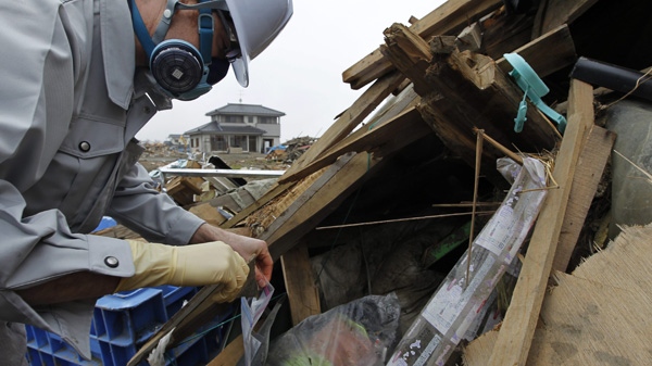 In this photo taken on April 22, 2011, EFA Laboratory manager Eric Eguina puts a piece of a material into a plastic bag while looking for materials possibly containing asbestos in an area devastated by the March 11 tsunami in Natori, Miyagi Prefecture, northeastern Japan. (AP Photo/Hiro Komae)