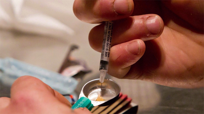A man draws heroin into a syringe