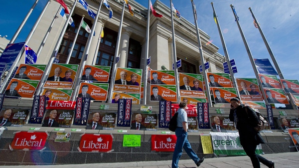 Pedestrians walk past the Government Conference Centre where Federal election signs are posted outside prior to the English language federal election debate in Ottawa Ont., on Tuesday, April 12, 2011. (Paul Chiasson / THE CANADIAN PRESS)