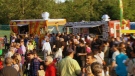 People line up in front of food truck vendors at Woodbine Park during the Beaches Jazz Festival in Toronto on Thursday, July 25, 2013.

