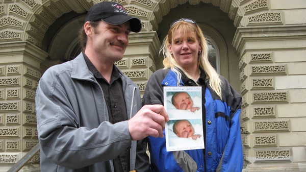Richard Brant smiles as he shows pictures of his infant son, Dustin, who died of pneumonia, as Dustin's mother Mary Farrell looks on outside the Ontario Court of Appeal court in Toronto, Wednesday May 4, 2011. (Pat Hewitt / THE CANADIAN PRESS)