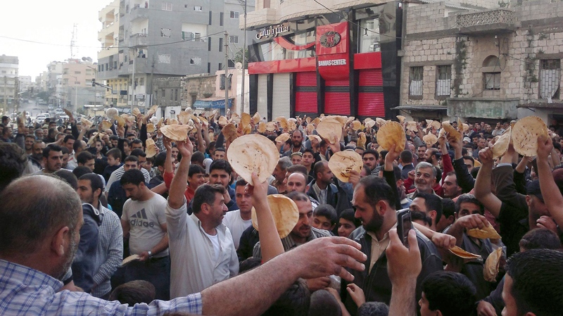Syrian men carry bread loaves during a protest against Syrian President Bashar Assad's regime, in the coastal town of Banias, Syria, Tuesday, May 3, 2011. (AP)