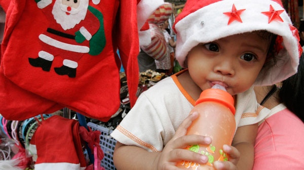 A baby girl sucks from her feeding bottle as they attend to their sidewalk stall in Manila, Philippines, Tuesday, Dec. 14, 2010. (AP / Pat Roque)