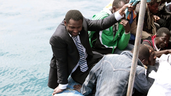 A man wearing a suit arrives on a boat along with some 250 migrants approaching the tiny Italian island of Lampedusa's harbor, Italy, Friday, May 6, 2011. (AP Photo/Francesco Malavolta) 