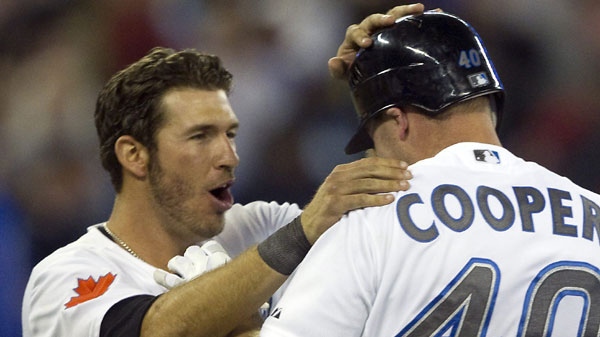 Toronto Blue Jays catcher J.P. Arencibia (left) congratulates teammate David Cooper after his sac-fly scored the game winning walk off run in 10th inning AL action in Toronto on Tuesday May 10, 2011. (Frank Gunn/THE CANADIAN PRESS)