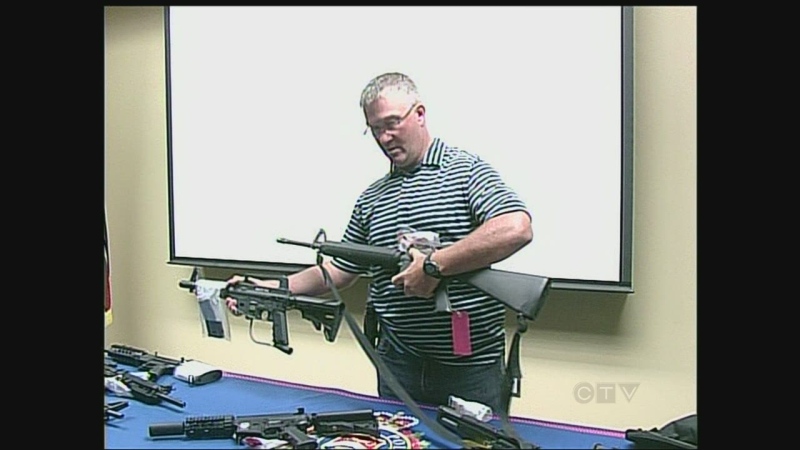 London police Det. Mark McGugan demonstrates paint ball and Airsoft guns, compared to real guns, in London, Ont. on Monday, August 12, 2013.