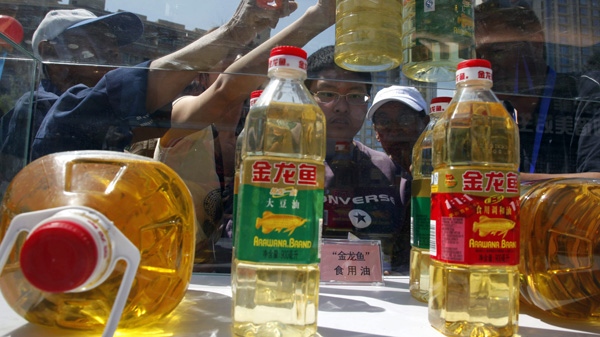Chinese residents try to tell counterfeit cooking oil products from the real products during an event to promote awareness of economic crimes in Beijing, China, Sunday, May 15, 2011. (AP Photo/Ng Han Guan)