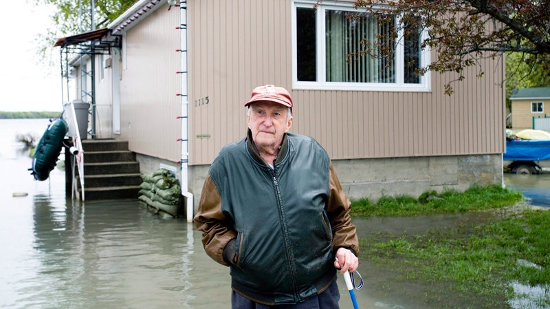 Donald Racine stands in his yard immersed in flood waters in the town of St-Blaise, Que., Tuesday, May 17, 2011. (Graham Hughes / THE CANADIAN PRESS)