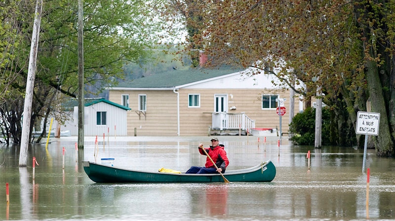A man paddles canoe through a flooded street in the town of St-Blaise, Que., Tuesday, May 17, 2011. (Graham Hughes / THE CANADIAN PRESS)