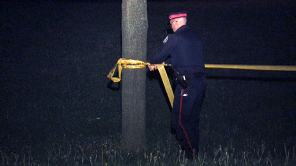 A police officer strings up police tape near the scene of a shooting at Skymark Park in Toronto on Monday, May 23, 2011.