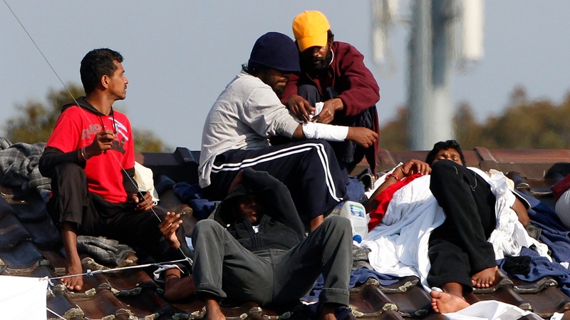 An asylum seeker places bandages on a fellow detainee as they protest on the roof of the Villawood detention center in Sydney, Australia, Tuesday, Sept. 21, 2010. (AP / Rob Griffith)