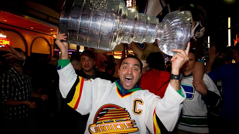 A Vancouver Canucks fan hoists a replica of the Stanley Cup over his head as people pack Granville Street in celebration after the Vancouver Canucks advanced to the NHL's Stanley Cup Final after defeating the San Jose Sharks 4 games to 1 in Vancouver, B.C., on Tuesday, May 24, 2011. (Darryl Dyck  / THE CANADIAN PRESS)