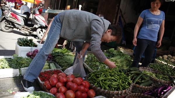 A customer picks vegetables to buy at a street vendor in Shanghai, China on Tuesday May 24, 2011. (AP Photo/Eugene Hoshiko)