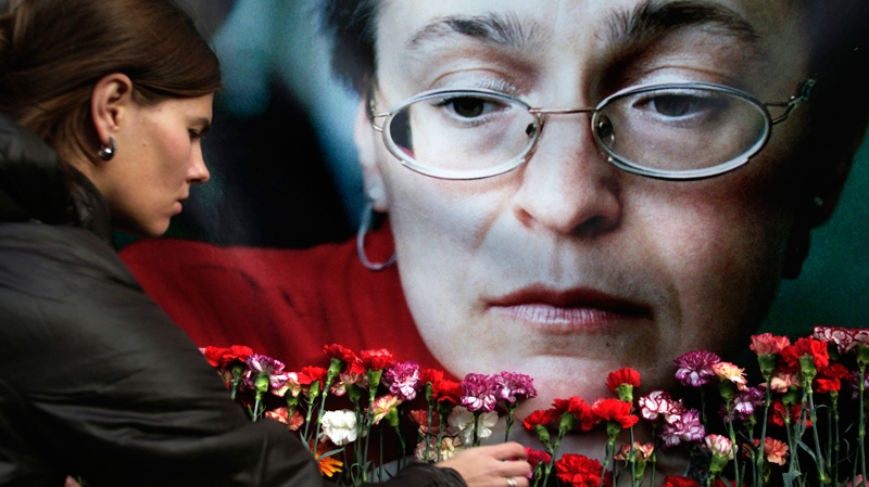 A woman places flowers at a portrait of slain journalist Anna Politkovskaya, during a rally in downtown Moscow, Wednesday, Oct. 7, 2009. (AP / Pavel Golovkin)