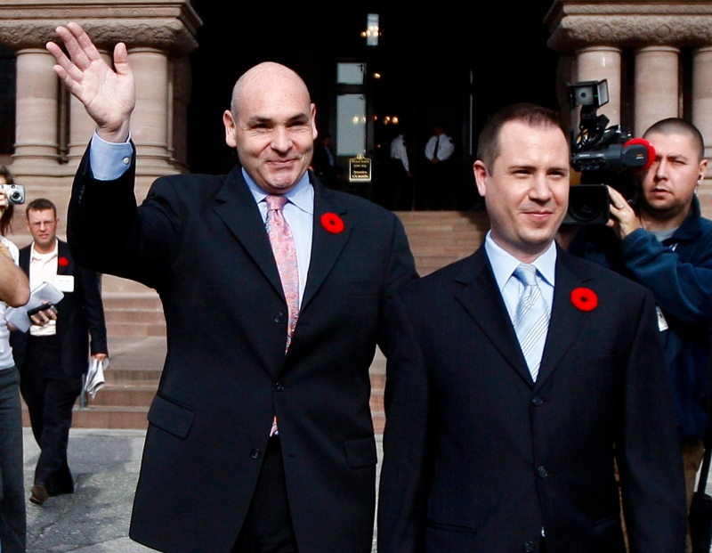 George Smitherman, left, and his husband Christopher Peloso, right, wave as they leave Queen's Park on Monday, Nov. 9, 2009 in Toronto. (Nathan Denette / THE CANADIAN PRESS)