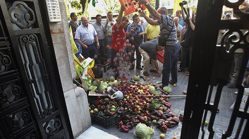 Protesting farmers dump some 300 kilos (700 pounds) of fruit and vegetables, cabbage, tomatoes, peppers, cucumbers and other produce outside the German consulate in Valencia, Spain Thursday June 2, 2011. (AP / Robert Solsona)