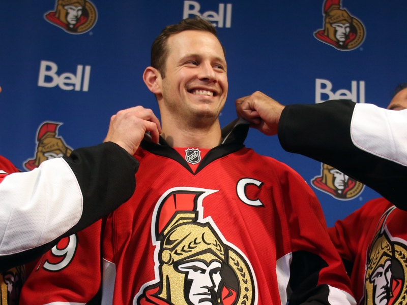 Ottawa Senators' Jason Spezza (centre) has his captain's team jersey adjusted by assistant captains Chris Neil (left) and Chris Phillips(right) after he was named the team's captain in Ottawa, Saturday Sept. 14, 2013. (THE CANADIAN PRESS/Fred Chartrand)
