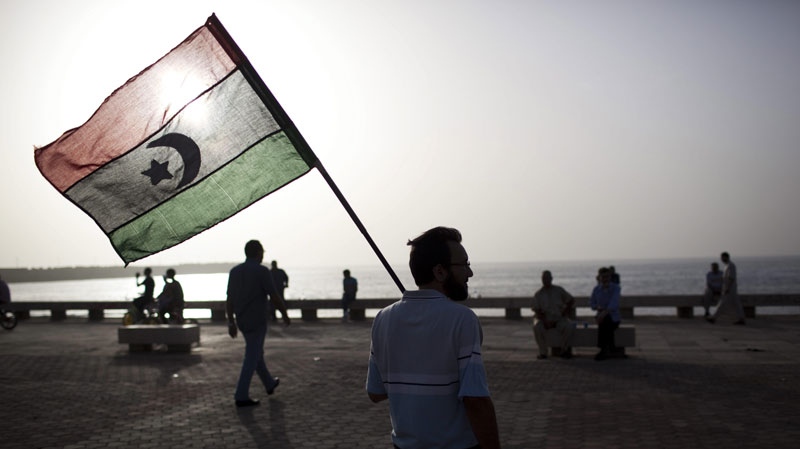 A man holds a pre-Gadhafi era national flag in Benghazi, Libya, Sunday, June 5, 2011. (AP Photo/Rodrigo Abd)