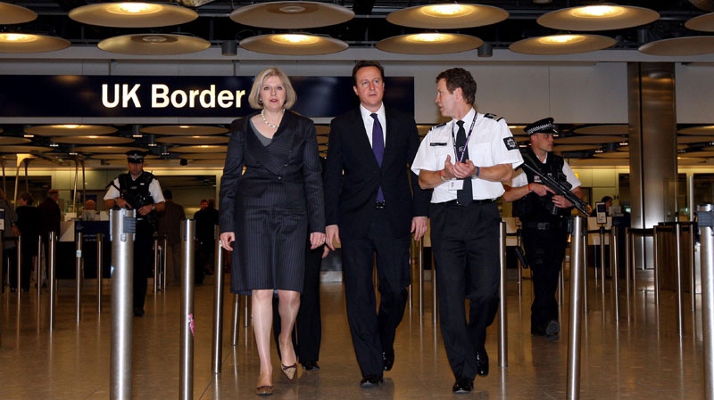 British Prime Minister David Cameron, center, and Home Secretary Theresa May, left, visit the UK Border Agency staff at Terminal 5 of Heathrow Airport, London where they were shown differences between fake and real passports Tuesday Nov. 23, 2010. (AP Photo/ Steve Parsons, Pool)