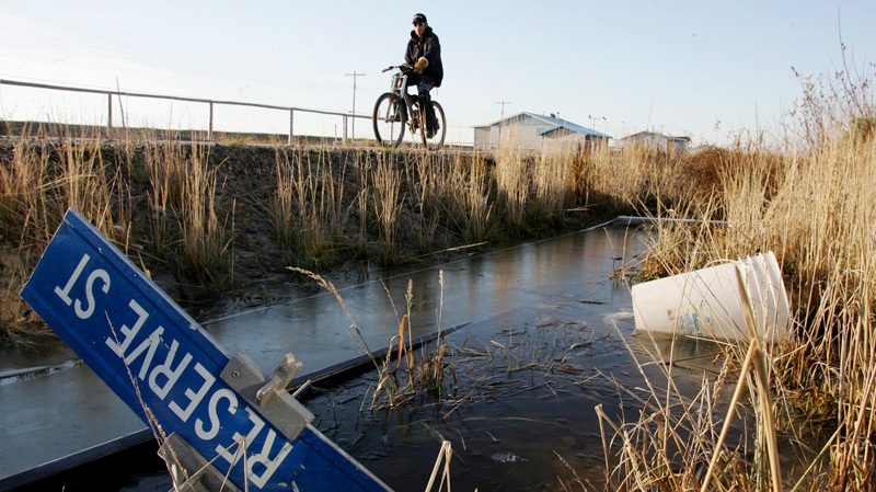 Kenny Wynne rides his bike along a road on the Kashechewan native reserve in northern Ontario on Oct. 28, 2005. (Jonathan Hayward / THE CANADIAN PRESS)
