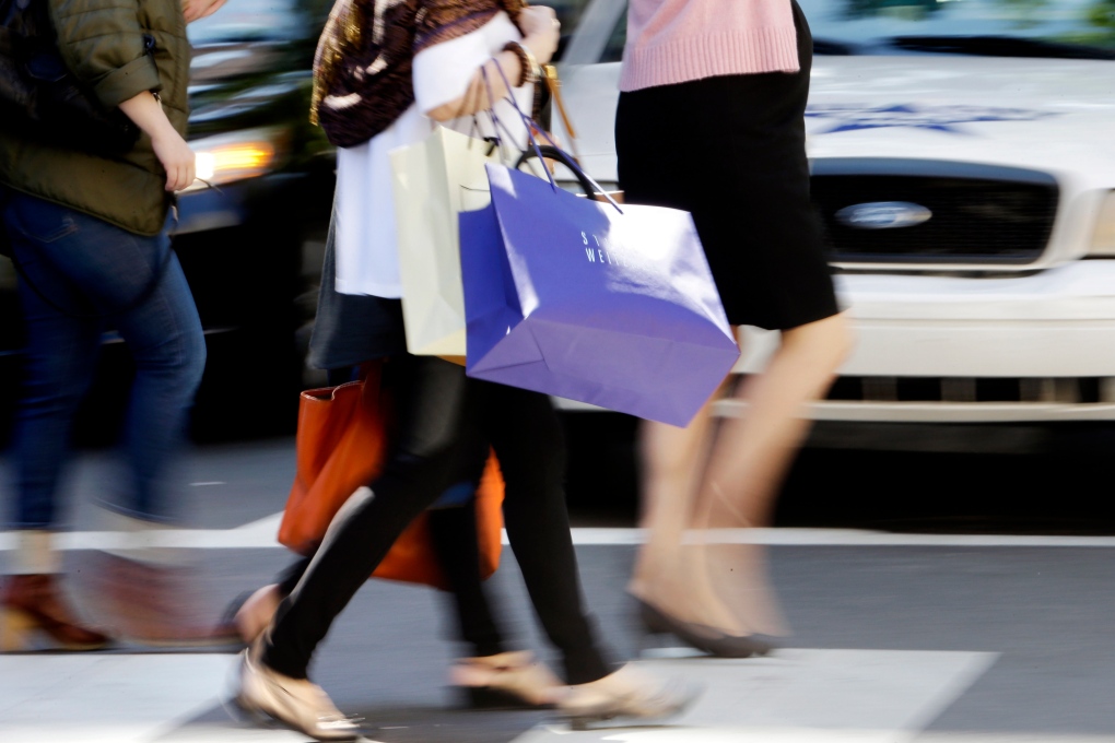 pedestrians with shopping bags cross a street
