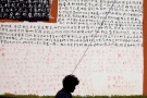 A woman walks past a wall covered with Chinese characters from chapters of John Rawls' book "A Theory of Justice" outside an art gallery in Beijing Thursday, Aug. 29, 2013. (AP / Alexander F. Yuan)
