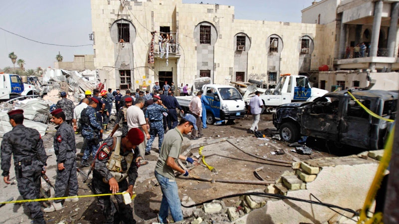 Iraqi security forces inspect the scene of a suicide car bomb attack in Basra, Iraq's second-largest city, 340 miles (550 kilometers) southeast of Baghdad, Iraq, Monday, June 13, 2011. (AP Photo)
