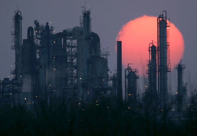 A Pioneer oil refinery is silhouetted against the setting sun in El Dorado, Kan. (AP / Charlie Riede)