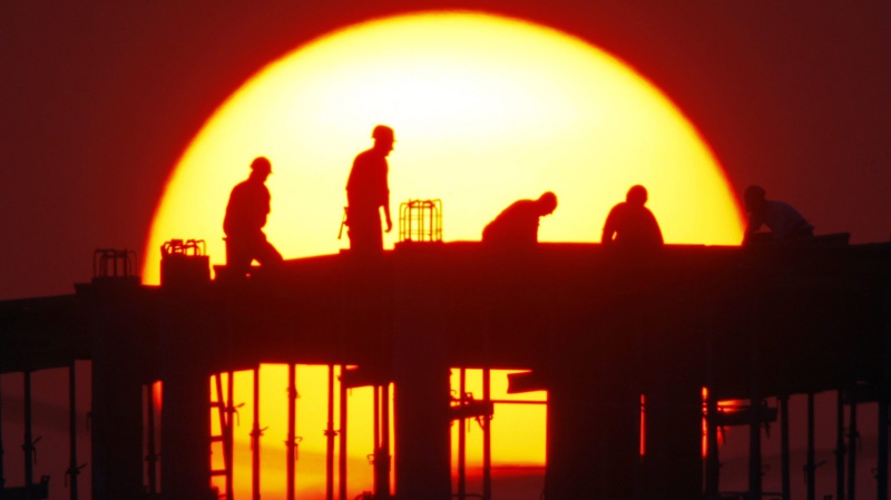 House-builders are silhouetted against the sunset in Minsk, Belarus, Wednesday, Apr. 27, 2011. (AP Photo/Sergei Grits)