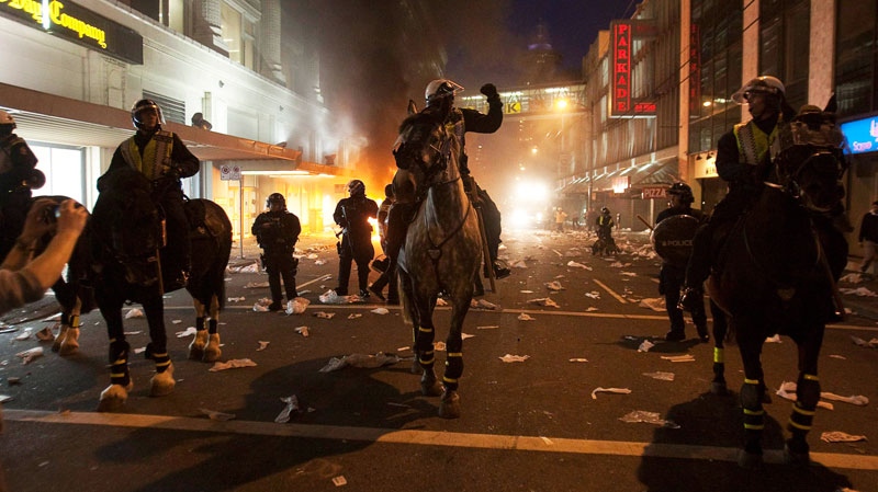 Police on horseback move down a street during a riot in downtown Vancouver, Wednesday, June 15, 2011. THE CANADIAN PRESS / Ryan Remiorz