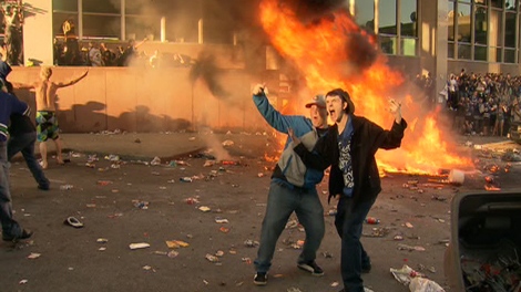 Rioters pose in front of a large fire during a riot following the Vancouver Canucks 4-0 loss to the Boston Bruins in game 7 of the Stanley Cup hockey final in Vancouver, Wednesday, June 15, 2011.