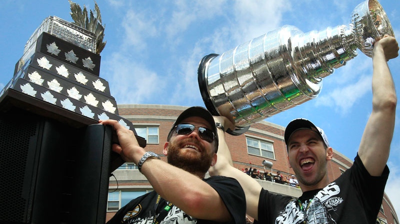 Boston Bruins captain Zdeno Chara, right, hoists up the Stanley Cup as goalie Tim Thomas, left, holds onto the Conn Smythe trophy during a rally in celebration of their NHL hockey Stanley Cup playoff victory in Boston, Saturday, June 18, 2011. (AP Photo/Charles Krupa)