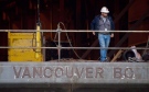 A Seaspan Vancouver Shipyards worker stands on a barge under construction in North Vancouver, B.C. in 2011. (Darryl Dyck / THE CANADIAN PRESS)