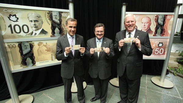 Mark Carney, Governor of the Bank of Canada, left, Finance Minister Jim Flaherty and RCMP Commissioner William Elliott unveil the new polymer bank note series at the Bank of Canada's head office in Ottawa, Monday, June 20, 2011. (Bank of Canada / The Canadian Press Images)