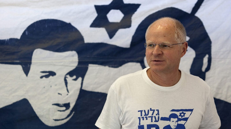 Noam Schalit walks past a banner depicting his son, captured Israeli soldier Gilad Schalit prior to a meeting with French Foreign Minister Alain Juppe at a protest tent near the Prime minister's office in Jerusalem, Thursday, June 2, 2011. (AP Photo/Sebastian Scheiner)