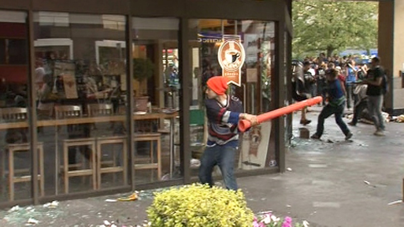A Vancouver Canucks fan prepares to smash a window at a Blenz Coffee shop during a riot in downtown Vancouver on Wednesday, June 15, 2011.