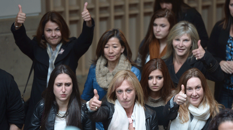 Rachael Szendrei, centre, wearing a white scarf, the mother of Laura Szendrei, gives the thumbs up as she and supporters leave court following verdict at the provincial court in Surrey, B.C., on Friday, Oct. 18, 2013.A judge has sentenced a young man who murdered 15-year-old Laura Szendrei in a suburban park near Vancouver three years ago as an adult. THE CANADIAN PRESS/Jonathan Hayward