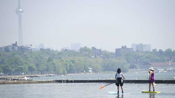 Two women use paddle boards on Lake Ontario just off the boardwalk along Lakeshore Blvd., in Toronto on Tuesday, May 31, 2011. The temperature on the day was expected to hit 31C. (Nathan Denette / THE CANADIAN PRESS)