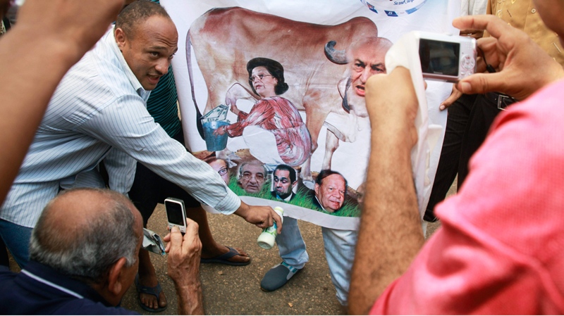 Egyptian protesters surround a poster showing the face of ousted President Hosni Mubarak and his family on a bull face at Tahrir Square in Cairo, Egypt, Monday, July 11, 2011 during the fourth day of protest.  (AP / Amr Nabil) 